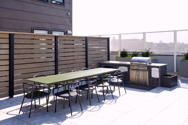 Outdoor space at VERVE Columbus with dining table, chairs, and a grill.