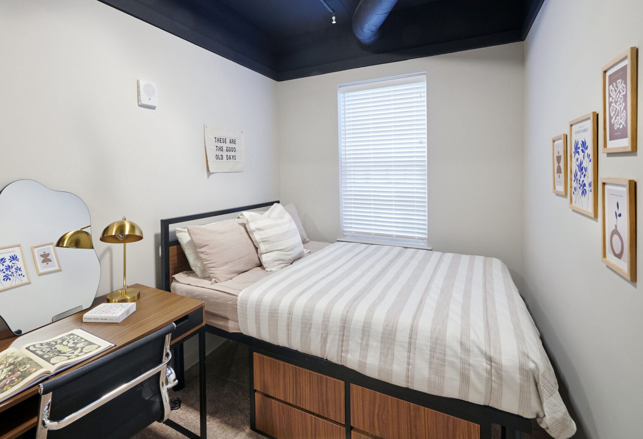 Stylish student bedroom at VERVE Columbus featuring a cozy bed with white pillows, a wood desk with a reading lamp and books, and college-inspired wall decor—designed for comfort and focus.