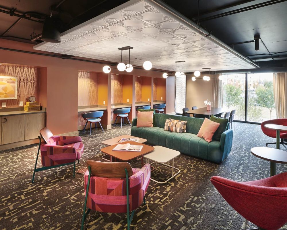 Vibrant resident lounge at VERVE Columbus featuring colorful seating, cozy booths with built-in desks, statement lighting, and large windows—designed for studying, socializing, or just vibing out.