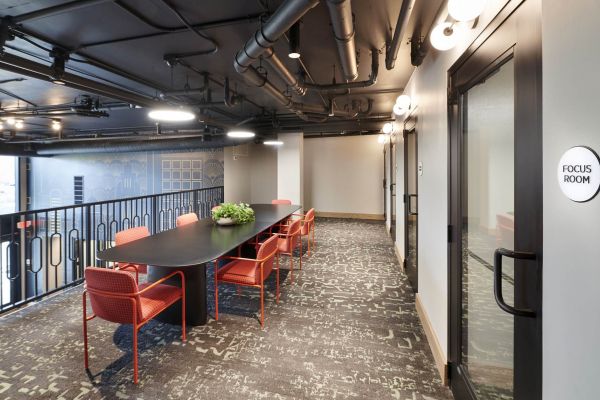 Study area at VERVE Columbus with a long table, red chairs, and industrial-style ceiling.
