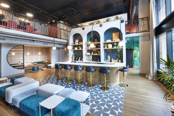 Stylish resident lounge at VERVE Columbus featuring a modern bar with blue arch shelving, gold accents, bold tile flooring, and plush seating designed for casual hangouts or study sessions.