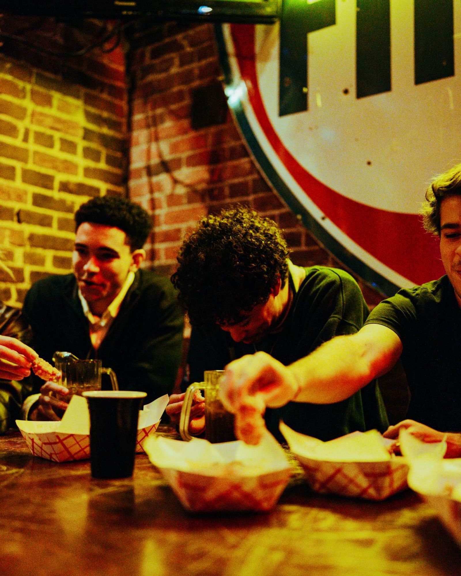 Group of friends enjoying food together at a casual restaurant near VERVE Columbus, surrounded by exposed brick walls and warm lighting that capture the local dining vibe.