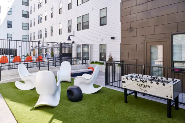 Outdoor courtyard at VERVE Columbus featuring modern sculptural lounge chairs, artificial turf, and a foosball table—creating a fun and relaxed social space for residents.