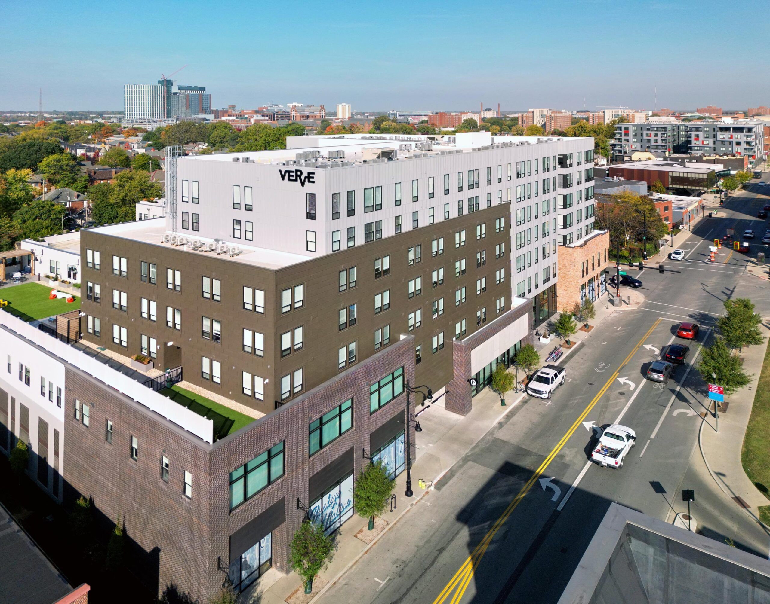 Daytime aerial view of VERVE Columbus showcasing its contemporary architecture and central location along a busy city street, with downtown Columbus visible in the distance.